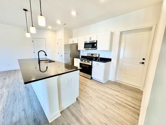 A kitchen with white cabinets and a black countertop.