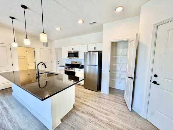 A kitchen with a black granite countertop and white cabinets.
