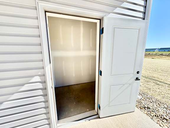 A white door is open to a room with a beach in the background.