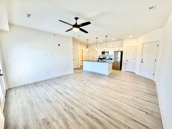 A spacious room with a ceiling fan and a kitchen island in the middle.