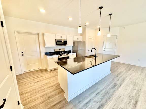 A modern kitchen with a large island and pendant lights.