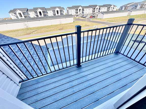 A balcony with a black railing and a wooden floor.