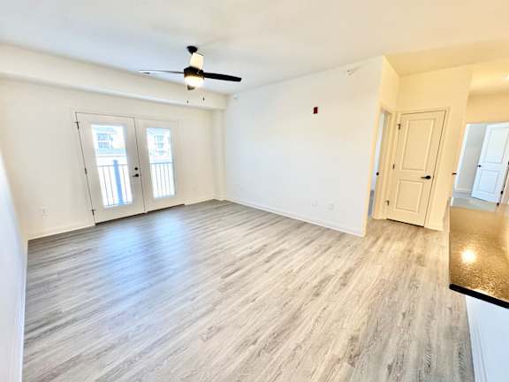 A room with a ceiling fan and light fixture, two doors, and a window.