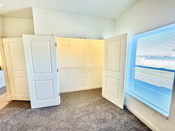 A room with a carpeted floor and a window with blinds.