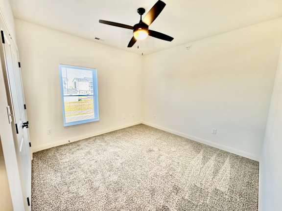 A room with a ceiling fan and a window with blinds.