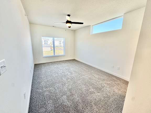 A room with a ceiling fan and carpeted floor.