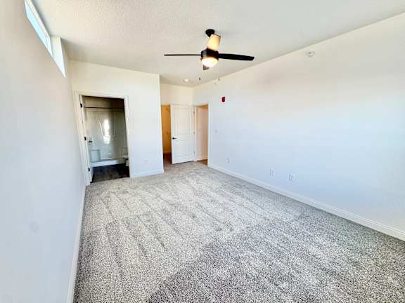 A room with a ceiling fan and carpeted floor.