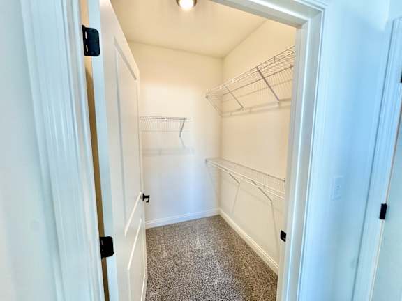 A white pantry with a door open to a hallway.