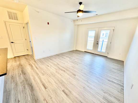 A room with a ceiling fan and wood flooring.