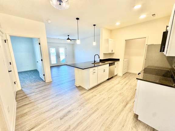 A kitchen with white cabinets and a black countertop.