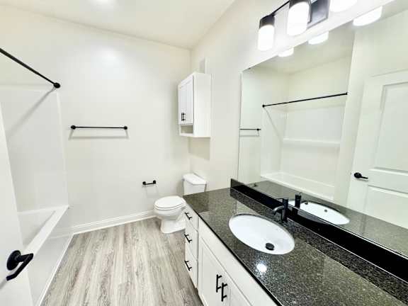 A bathroom with a toilet, sink, and mirror.