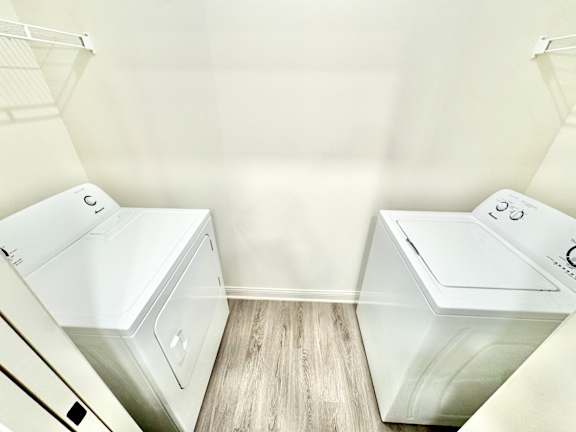 Two white washing machines in a laundry room.