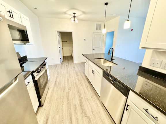 A kitchen with stainless steel appliances and wooden floors.