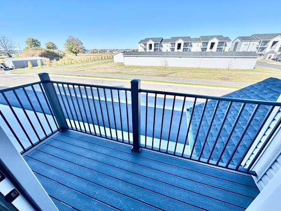 A balcony with a black railing and a blue wooden floor.