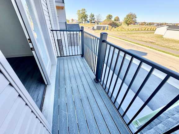 A balcony with a black railing and wooden floor.