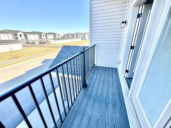 A balcony with a black railing and a blue wooden floor.