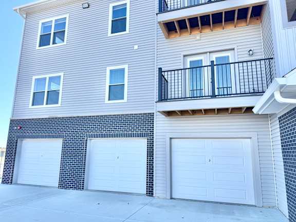 A two-story building with a balcony on the upper floor and three garage doors.