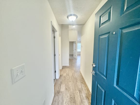 a hallway with a blue door and white walls and wood floors at Hawthorne Properties in Lafayette, IN 47905