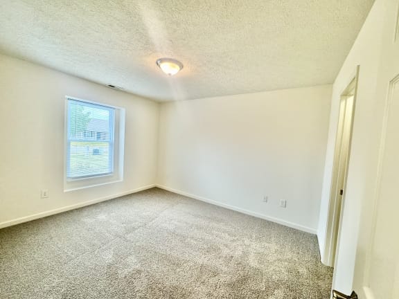 an empty room with carpet and a window at Hawthorne Properties in Lafayette, IN 47905