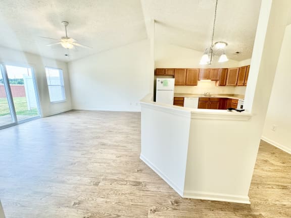 an empty living room with a kitchen and a ceiling fan at Hawthorne Properties in Lafayette, IN 47905