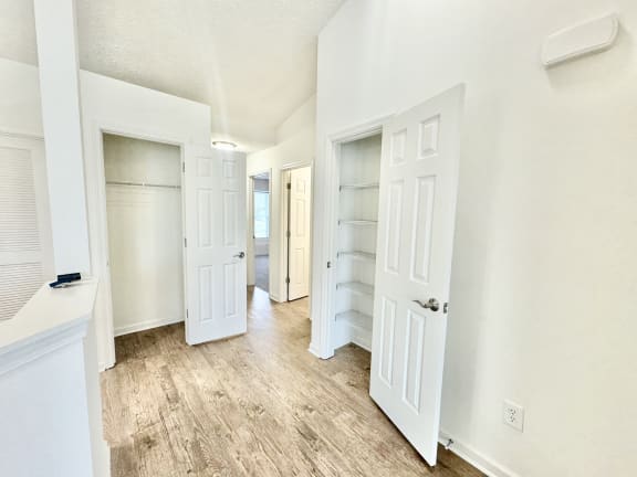 an empty room with white doors and a hallway with white closets at Hawthorne Properties in Lafayette, IN 47905