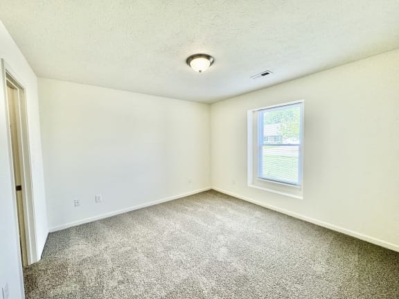 an empty room with carpet and a window