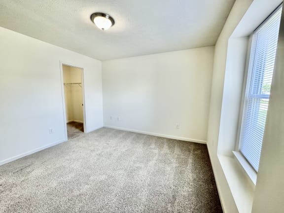 an empty living room with carpet and a door to a closet at Hawthorne Properties in Lafayette, IN 47905