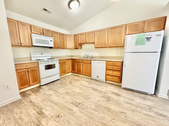 an empty kitchen with white appliances and wooden cabinets at Hawthorne Properties in Lafayette, IN 47905