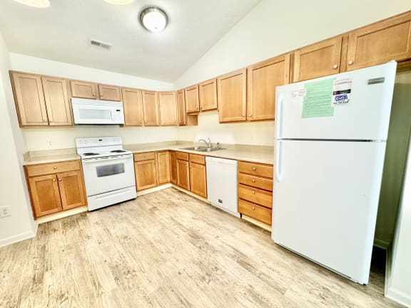 an empty kitchen with wooden cabinets and white appliances at Hawthorne Properties in Lafayette, IN 47905