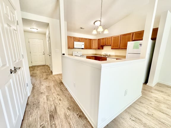 an empty kitchen with wood flooring and a white counter top
