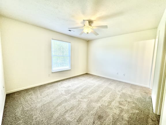 an empty living room with a ceiling fan and a window at Hawthorne Properties in Lafayette, IN 47905