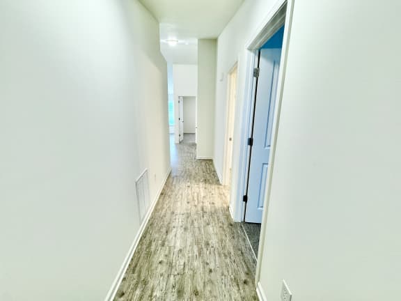 an empty hallway with white walls and a wood floor at Hawthorne Properties in Lafayette, IN 47905