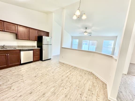 an empty kitchen and living room with wood flooring and white walls at Hawthorne Properties in Lafayette, IN 47905