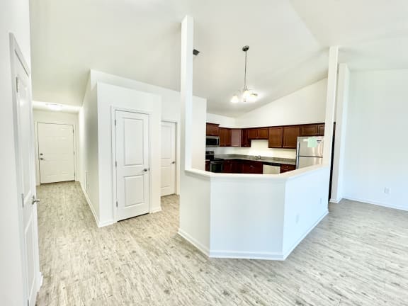 an empty living room and kitchen with white walls and wood flooring at Hawthorne Properties in Lafayette, IN 47905