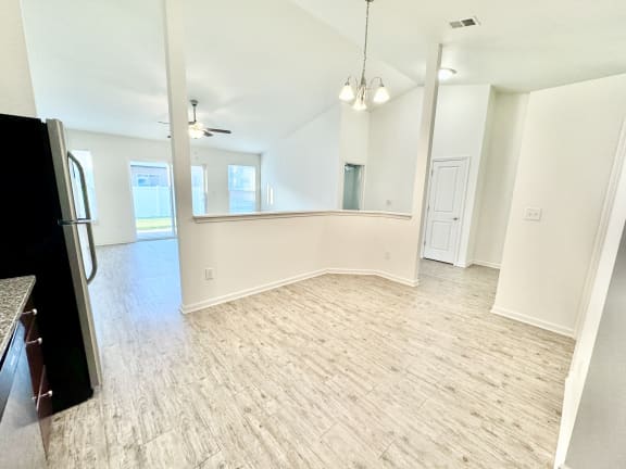 an empty living room with a kitchen and a refrigerator at Hawthorne Properties in Lafayette, IN 47905