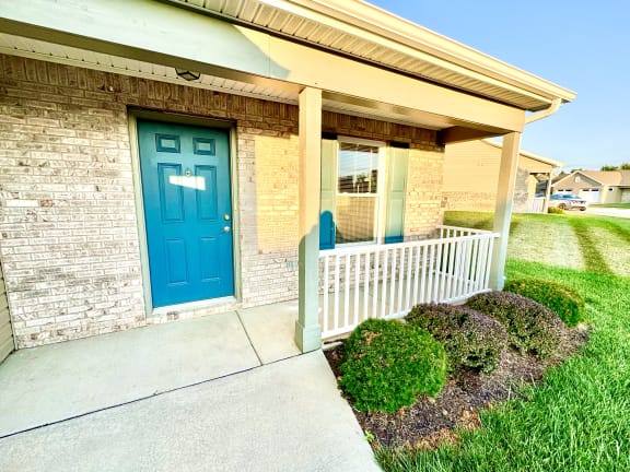 a blue door on the side of a building with a porch at Hawthorne Properties in Lafayette, IN 47905
