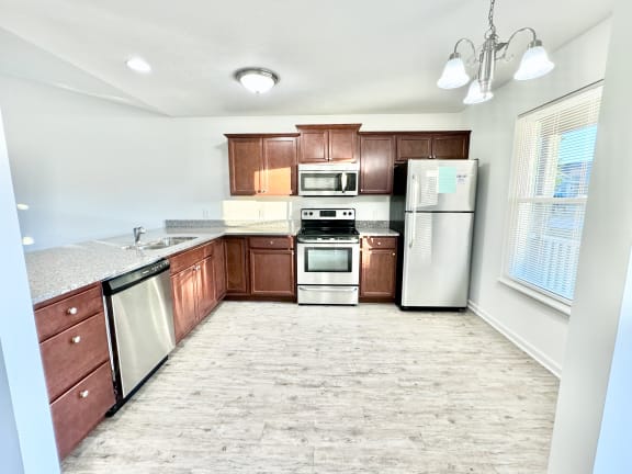 an empty kitchen with wooden cabinets and stainless steel appliances at Hawthorne Properties in Lafayette, IN 47905