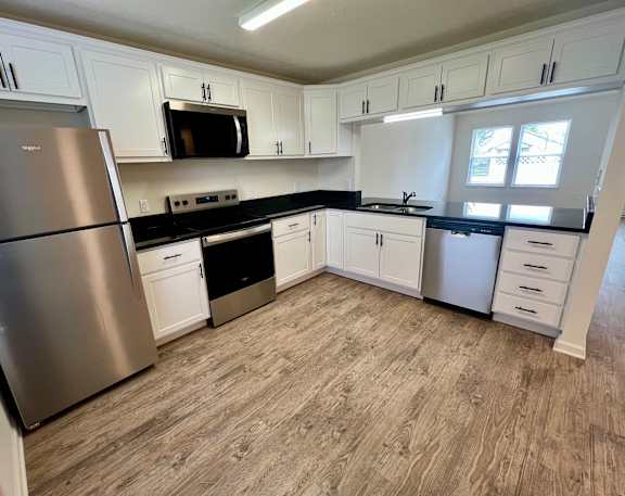 A kitchen with white cabinets and a stainless steel refrigerator.