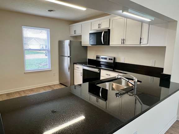 A kitchen with black countertops and white cabinets.