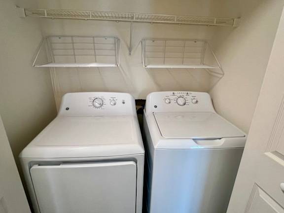 Two white front loading washing machines in a small laundry room.