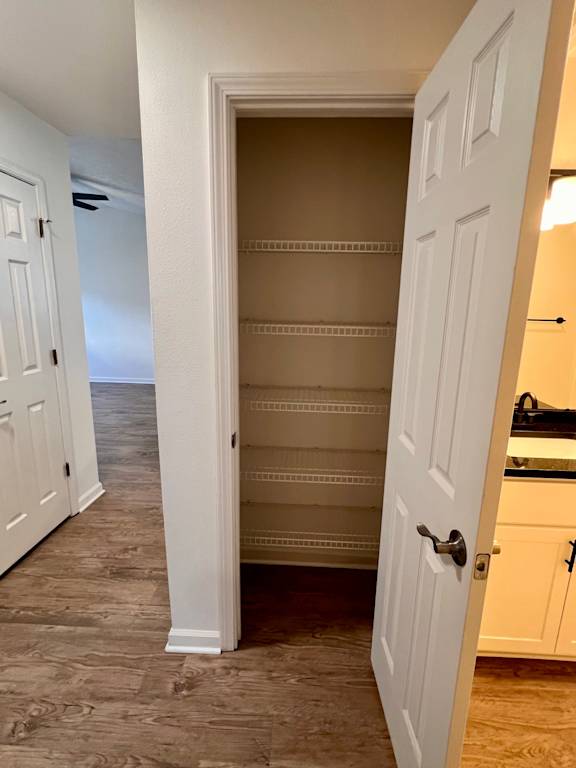 A white door is open to a room with a kitchen in the background.