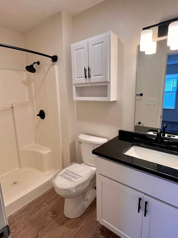 A white toilet with a black tank lid is in a bathroom with white walls.