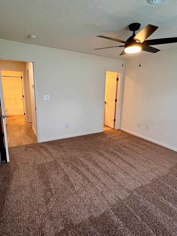 A room with a ceiling fan and carpeted floor.