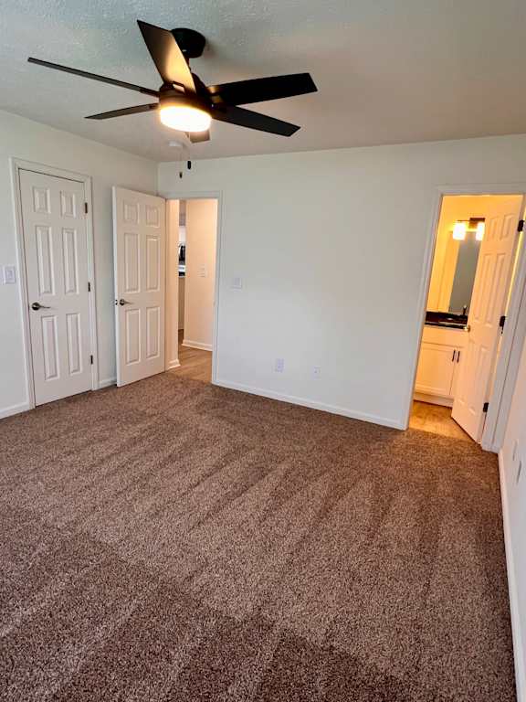 A room with a ceiling fan and carpeted floor.