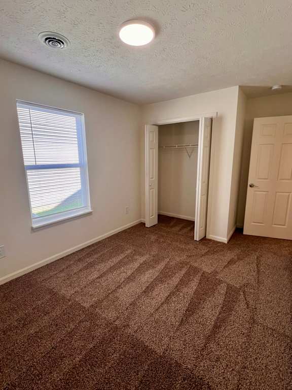 A room with a carpeted floor and a window with blinds.