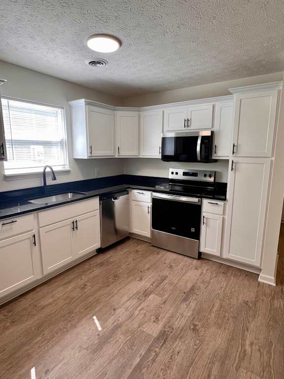 A kitchen with white cabinets and a black countertop.