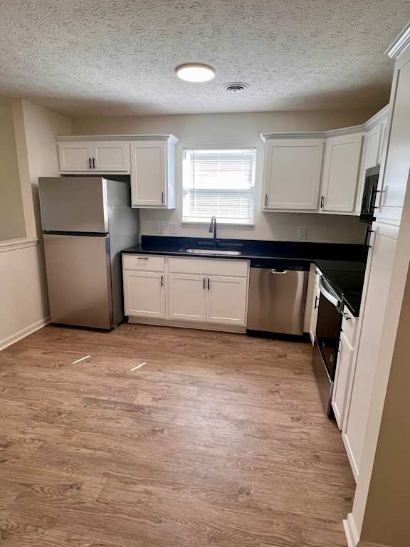 A kitchen with white cabinets and a stainless steel refrigerator.