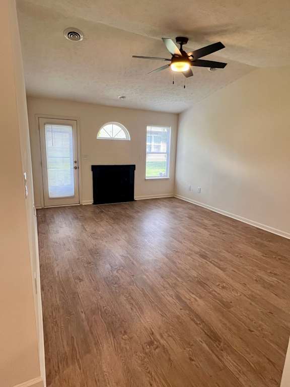 A room with a ceiling fan and wooden flooring.