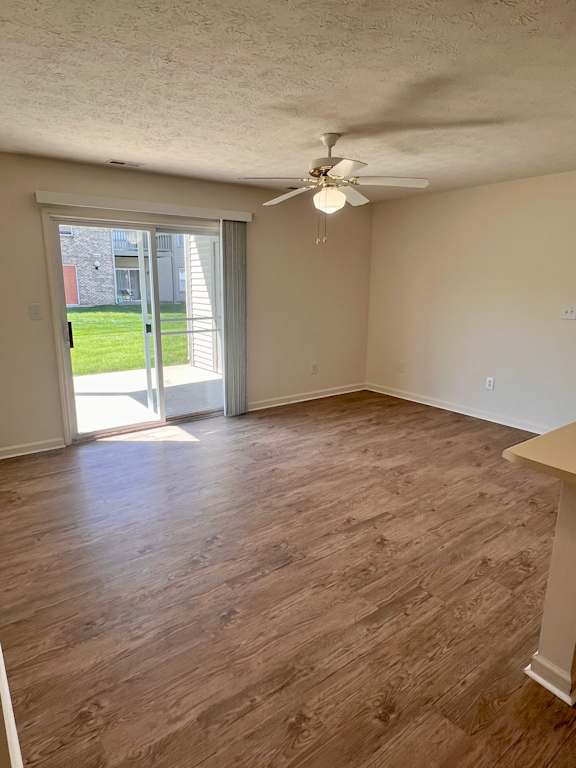 A room with a ceiling fan and sliding glass doors.