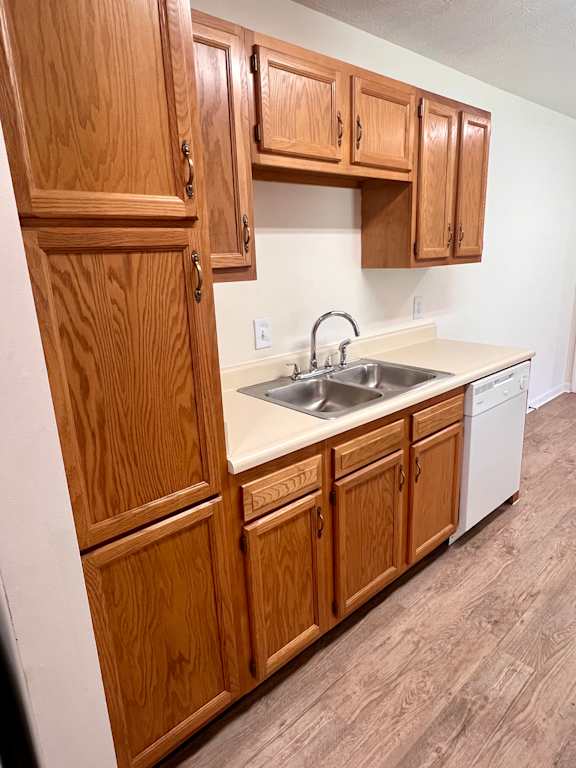 A kitchen with wooden cabinets and a white dishwasher.